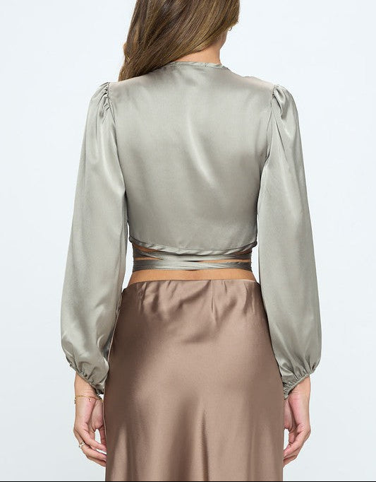 Woman wearing a light green satin blouse and brown skirt on a white background