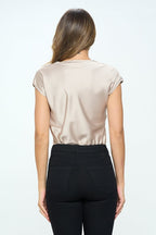 Woman wearing a beige satin top and black pants on a white background