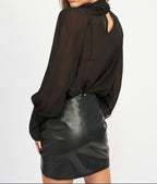 Woman wearing a black blouse and leather skirt on a white background