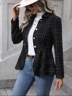 Woman wearing a black checkered blazer, white shirt, and blue jeans outdoors.
