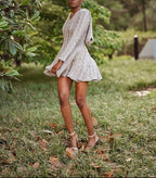 Woman in a light dress standing in a natural setting with trees and grass.